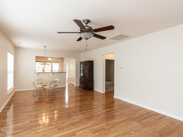 207 Callum Pl, Cary, NC 27519 - unfurnished living room with light wood-type flooring, a ceiling fan, baseboards, and a chandelier