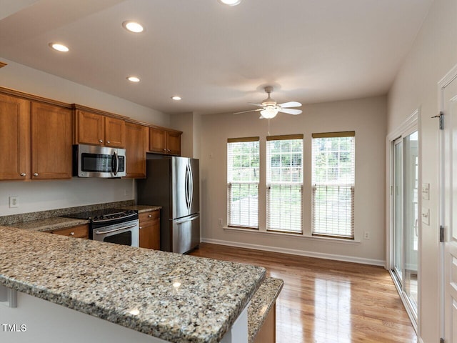 207 Callum Pl, Cary, NC 27519 - kitchen featuring stainless steel appliances, brown cabinetry, light wood-style flooring, a ceiling fan, and recessed lighting