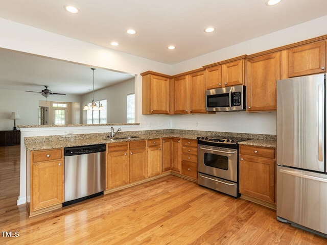 207 Callum Pl, Cary, NC 27519 - kitchen featuring appliances with stainless steel finishes, a sink, brown cabinets, light wood-style flooring, and a peninsula