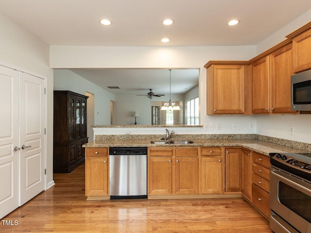 207 Callum Pl, Cary, NC 27519 - kitchen featuring appliances with stainless steel finishes, a sink, a peninsula, brown cabinetry, and recessed lighting