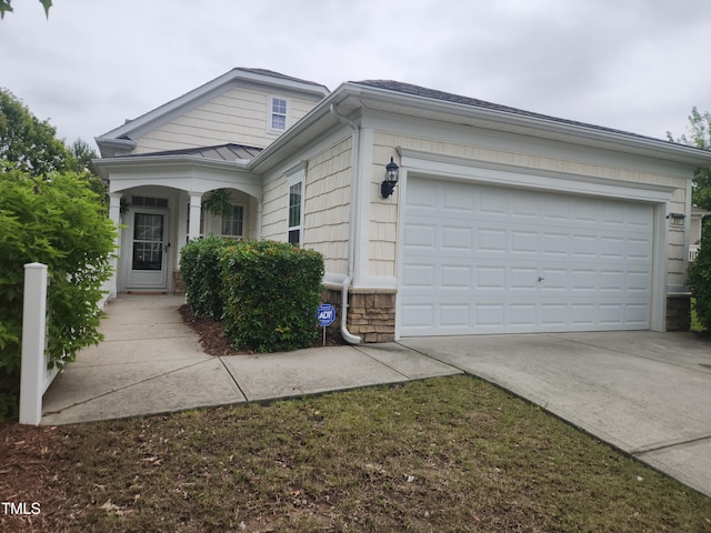 207 Callum Pl, Cary, NC 27519 - view of front of home with driveway, stone siding, a garage, and a standing seam roof