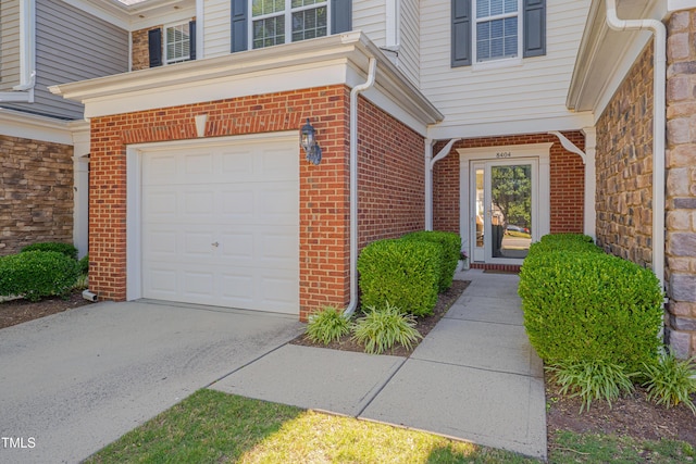 8404 Saltwood Pl, Raleigh, NC 27617 - doorway to property featuring an attached garage, brick siding, and driveway