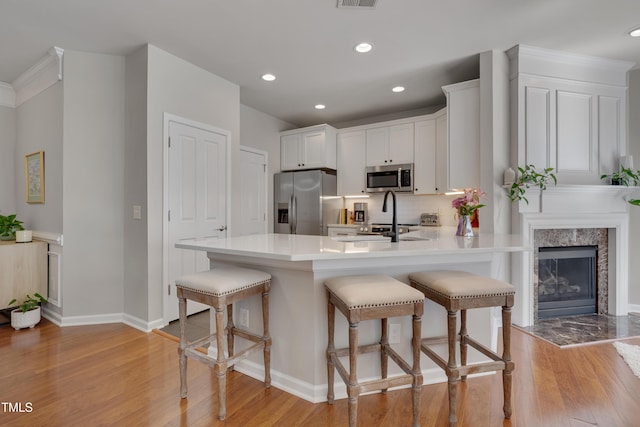 8404 Saltwood Pl, Raleigh, NC 27617 - kitchen with stainless steel appliances, light wood-type flooring, a peninsula, a kitchen bar, and decorative backsplash