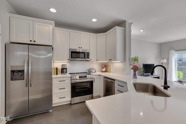 8404 Saltwood Pl, Raleigh, NC 27617 - kitchen featuring stainless steel appliances, a sink, white cabinetry, a peninsula, and decorative backsplash