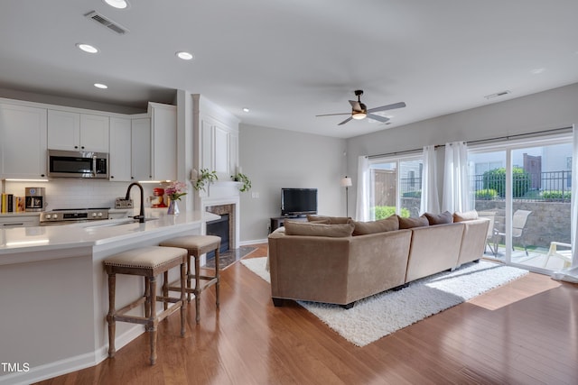8404 Saltwood Pl, Raleigh, NC 27617 - living area featuring wood finished floors, a fireplace, ceiling fan, baseboards, and recessed lighting