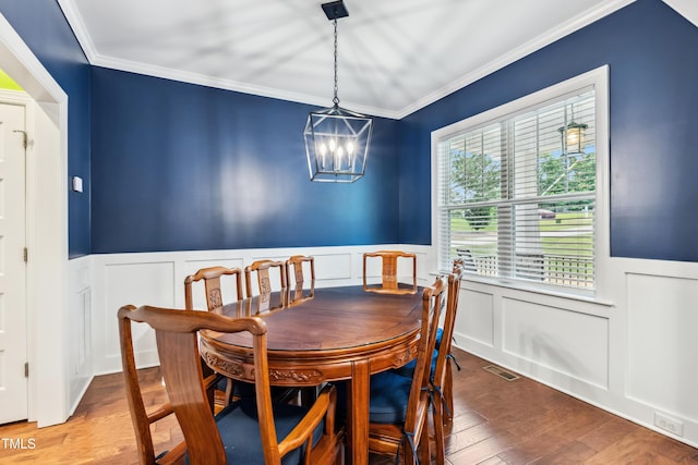 100 Lexington Ave, Zebulon, NC 27597 - dining room featuring crown molding, a decorative wall, a wainscoted wall, wood finished floors, and a chandelier
