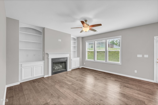 173 Forsyth Pkwy, Clayton, NC 27520 - unfurnished living room with ceiling fan, wood finished floors, baseboards, a fireplace, and built in shelves