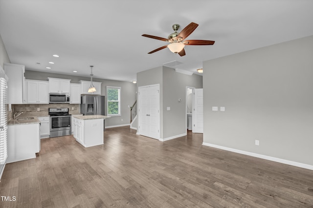 173 Forsyth Pkwy, Clayton, NC 27520 - kitchen with stainless steel appliances, a ceiling fan, open floor plan, a kitchen island, and white cabinetry