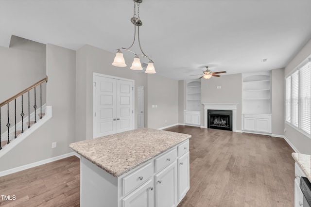 173 Forsyth Pkwy, Clayton, NC 27520 - kitchen with ceiling fan, light wood-style flooring, white cabinetry, built in shelves, and hanging light fixtures