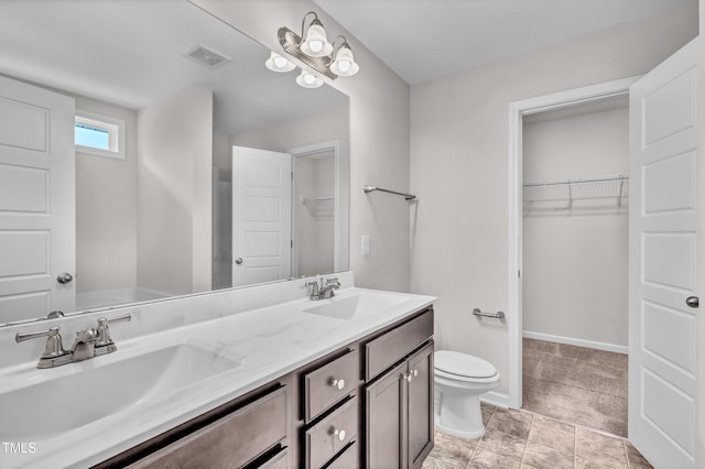 173 Forsyth Pkwy, Clayton, NC 27520 - bathroom with double vanity, toilet, a walk in closet, and baseboards