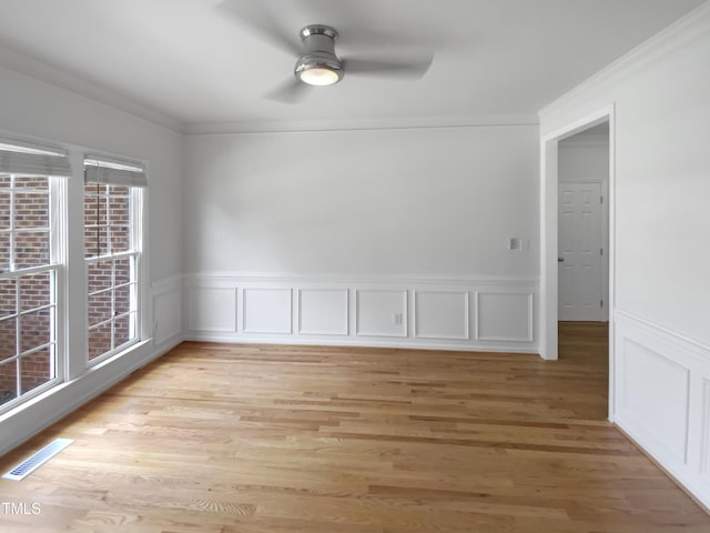 105 Crosswaite Way, Cary, NC 27518 - spare room featuring a ceiling fan, crown molding, light wood-style flooring, wainscoting, and a decorative wall