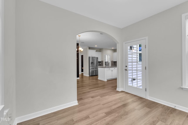 3449 S Beaver Ln, Raleigh, NC 27604 - spare room featuring arched walkways, light wood-type flooring, baseboards, and a chandelier