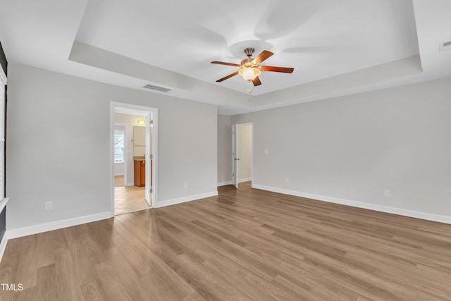 3449 S Beaver Ln, Raleigh, NC 27604 - unfurnished bedroom with a tray ceiling, light wood-style flooring, and baseboards