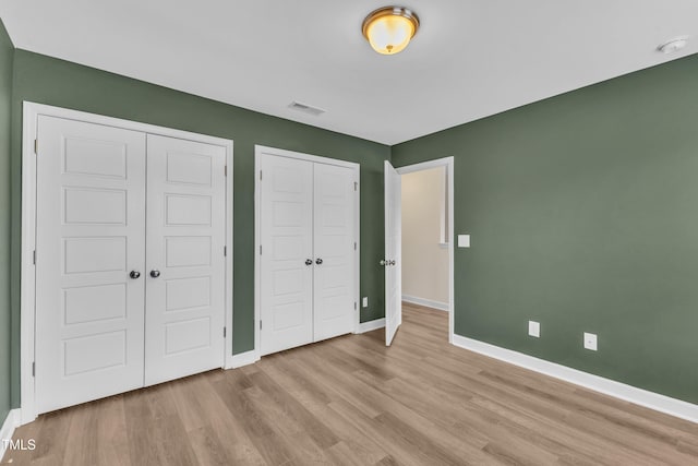 3449 S Beaver Ln, Raleigh, NC 27604 - unfurnished bedroom with baseboards, light wood finished floors, and multiple closets