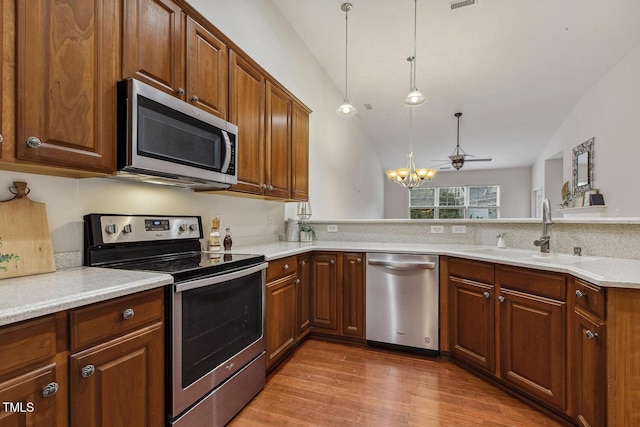 309 Plank Bridge Way, Morrisville, NC 27560 - kitchen with stainless steel appliances, a sink, wood finished floors, light countertops, and decorative light fixtures