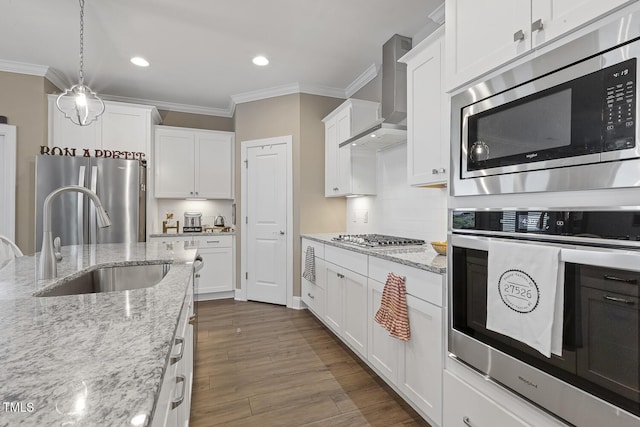 1374 Patriot Points Way, Fuquay Varina, NC 27526 - kitchen featuring appliances with stainless steel finishes, wall chimney range hood, crown molding, white cabinetry, and a sink