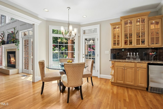 4021 Chaumont Dr, Apex, NC 27539 - dining space with wine cooler, a chandelier, healthy amount of natural light, light wood-style flooring, and ornamental molding