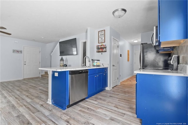 332 Dundee Cir, Raeford, NC 28376 - kitchen featuring stainless steel appliances, blue cabinetry, a peninsula, light wood-type flooring, and light countertops