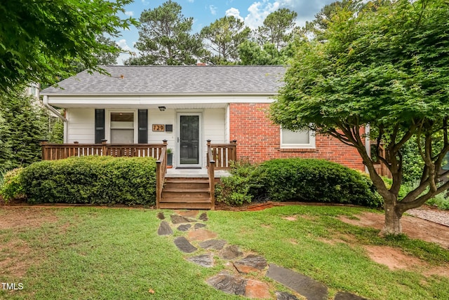 729 Mial St, Raleigh, NC 27608 - view of front facade featuring roof with shingles, covered porch, a front yard, and brick siding