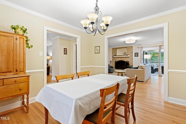 2805 Friendship Rd, Durham, NC 27705 - dining area with light wood-style floors, a chandelier, crown molding, a brick fireplace, and baseboards