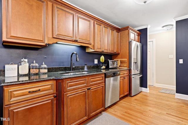 2805 Friendship Rd, Durham, NC 27705 - kitchen with stainless steel appliances, a sink, brown cabinetry, light wood-style flooring, and crown molding