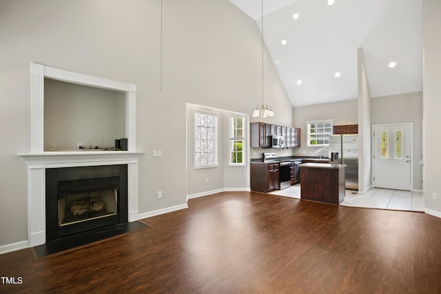 106 Gumdrop Path, Apex, NC 27502 - unfurnished living room featuring high vaulted ceiling, a fireplace with flush hearth, a chandelier, light wood-style flooring, and baseboards