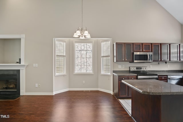 106 Gumdrop Path, Apex, NC 27502 - kitchen featuring appliances with stainless steel finishes, high vaulted ceiling, a chandelier, dark countertops, and dark wood-type flooring