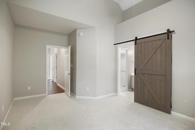 106 Gumdrop Path, Apex, NC 27502 - unfurnished bedroom featuring carpet floors, a barn door, baseboards, ensuite bathroom, and high vaulted ceiling