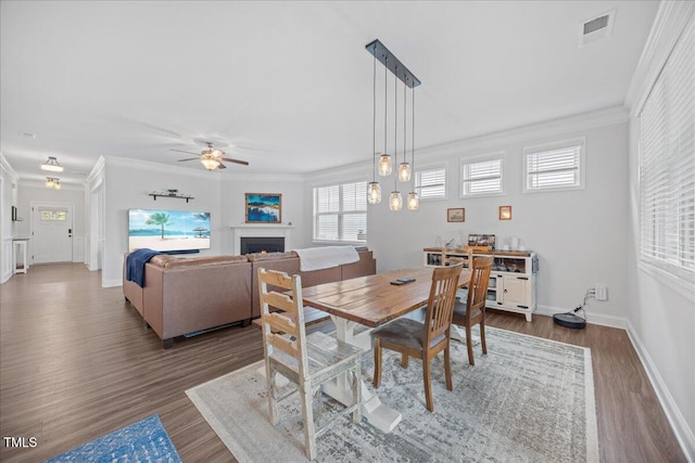 247 Axis Deer Ln, Garner, NC 27529 - dining space with a ceiling fan, wood finished floors, crown molding, a warm lit fireplace, and baseboards