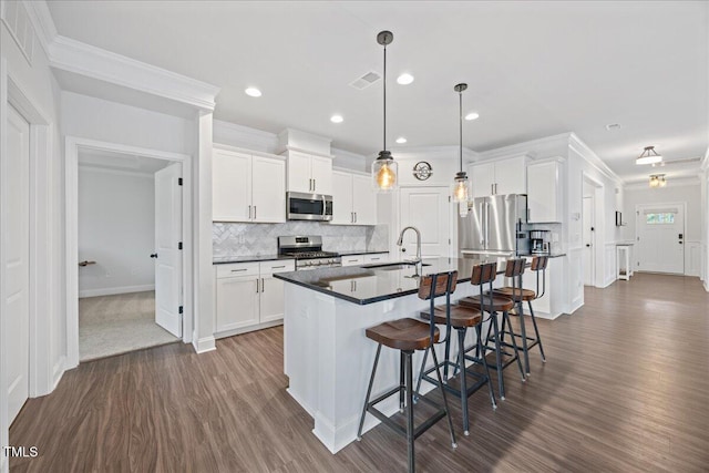 247 Axis Deer Ln, Garner, NC 27529 - kitchen with stainless steel appliances, dark wood-style flooring, a sink, ornamental molding, and a kitchen bar