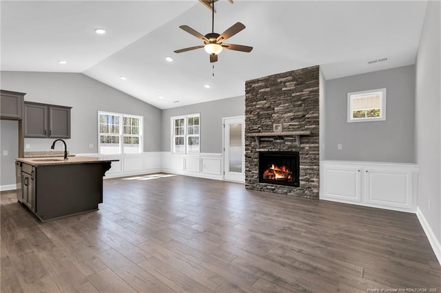 91 Laramie Ln, Selma, NC 27576 - unfurnished living room with a sink, ceiling fan, wainscoting, vaulted ceiling, and a stone fireplace