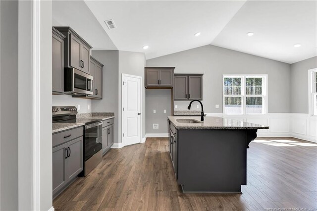 91 Laramie Ln, Selma, NC 27576 - kitchen featuring appliances with stainless steel finishes, a sink, vaulted ceiling, a kitchen island with sink, and light stone counters