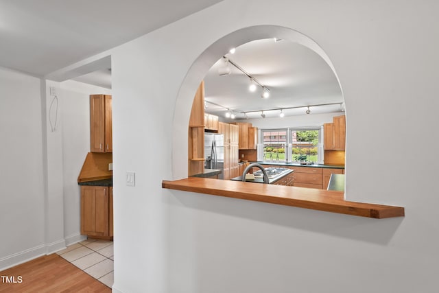 307 Country Club Dr, Durham, NC 27712 - kitchen with stainless steel fridge with ice dispenser, light wood-type flooring, track lighting, arched walkways, and dark countertops