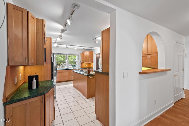307 Country Club Dr, Durham, NC 27712 - kitchen featuring track lighting, dark countertops, brown cabinets, baseboards, and freestanding refrigerator