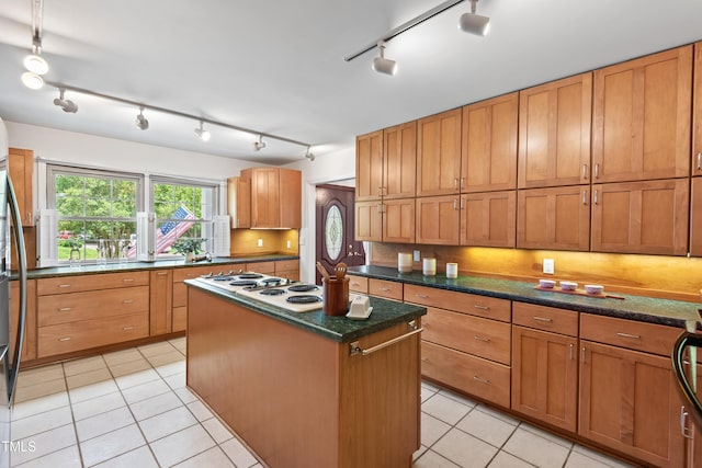 307 Country Club Dr, Durham, NC 27712 - kitchen featuring rail lighting, white stovetop, a kitchen island, light tile patterned floors, and backsplash