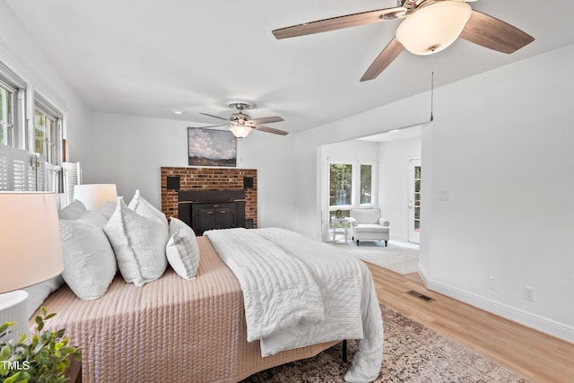 307 Country Club Dr, Durham, NC 27712 - bedroom featuring light wood-style floors, multiple windows, baseboards, and a brick fireplace