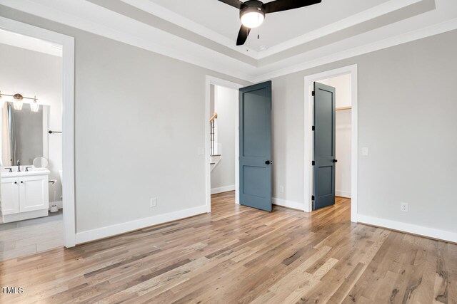 606 Velma Hopkins Ln, Raleigh, NC 27603 - unfurnished bedroom featuring light wood-type flooring, baseboards, ensuite bathroom, a tray ceiling, and a sink