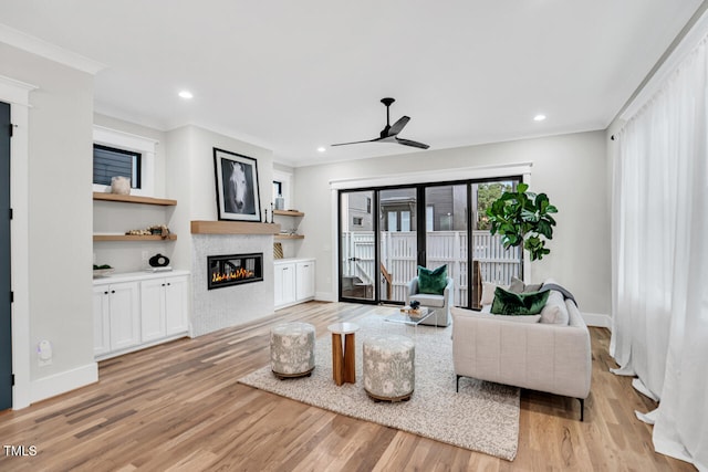 606 Velma Hopkins Ln, Raleigh, NC 27603 - living area with a glass covered fireplace, light wood-style floors, a ceiling fan, ornamental molding, and baseboards