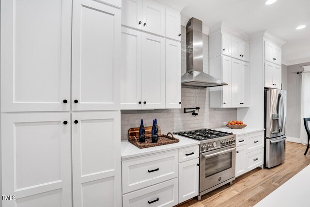 606 Velma Hopkins Ln, Raleigh, NC 27603 - kitchen with wall chimney range hood, stainless steel appliances, recessed lighting, tasteful backsplash, and light wood-style flooring