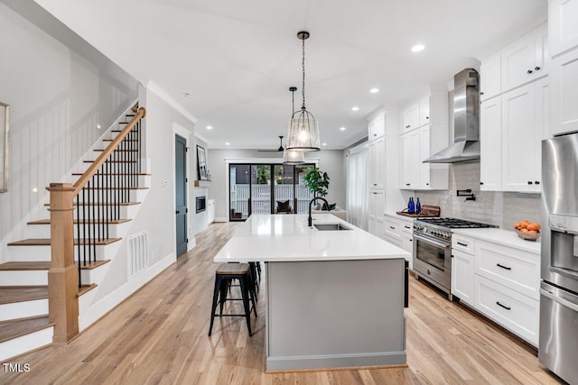 606 Velma Hopkins Ln, Raleigh, NC 27603 - kitchen featuring wall chimney exhaust hood, stainless steel appliances, a sink, tasteful backsplash, and light wood-type flooring