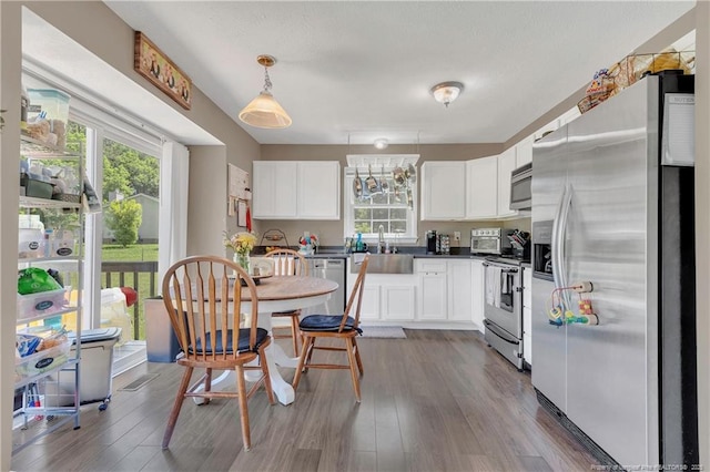 2251 Hackney Loop, Fayetteville, NC 28304 - kitchen with stainless steel appliances, white cabinetry, plenty of natural light, and wood finished floors