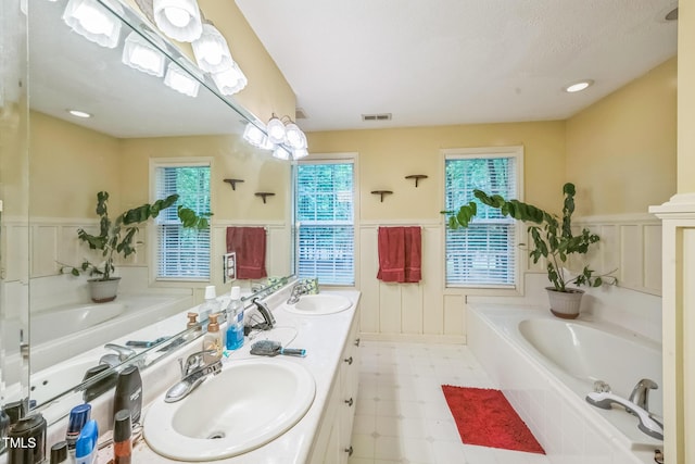 115 Redbay Ln, Clayton, NC 27527 - bathroom with wainscoting, a bath, double vanity, and tile patterned floors