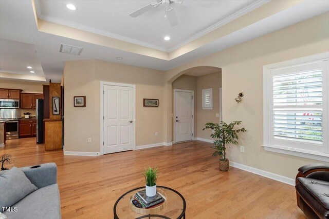 228 Ellisview Dr, Cary, NC 27519 - living room with a tray ceiling, arched walkways, a ceiling fan, ornamental molding, and light wood finished floors