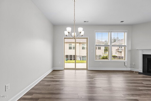 1102 Latitude Dr, Durham, NC 27713 - unfurnished dining area featuring a chandelier, dark wood-style flooring, a fireplace with flush hearth, and baseboards