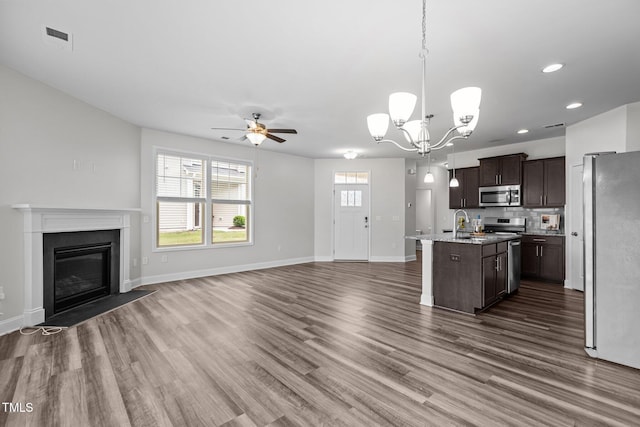 1102 Latitude Dr, Durham, NC 27713 - kitchen featuring appliances with stainless steel finishes, open floor plan, dark brown cabinetry, a kitchen island with sink, and dark wood-style flooring