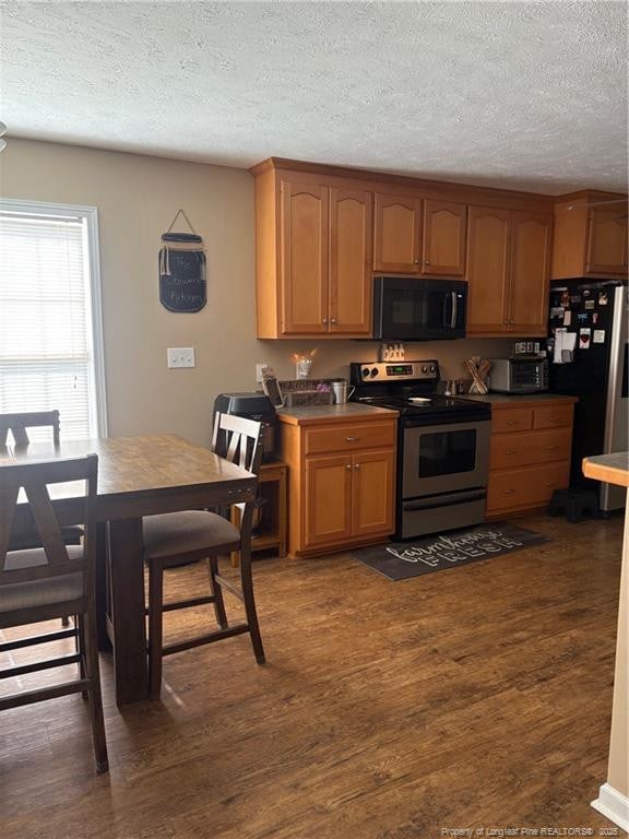 135 Paulownia Dr, Saint Pauls, NC 28384 - kitchen featuring black microwave, stainless steel electric stove, freestanding refrigerator, a textured ceiling, and dark wood-type flooring