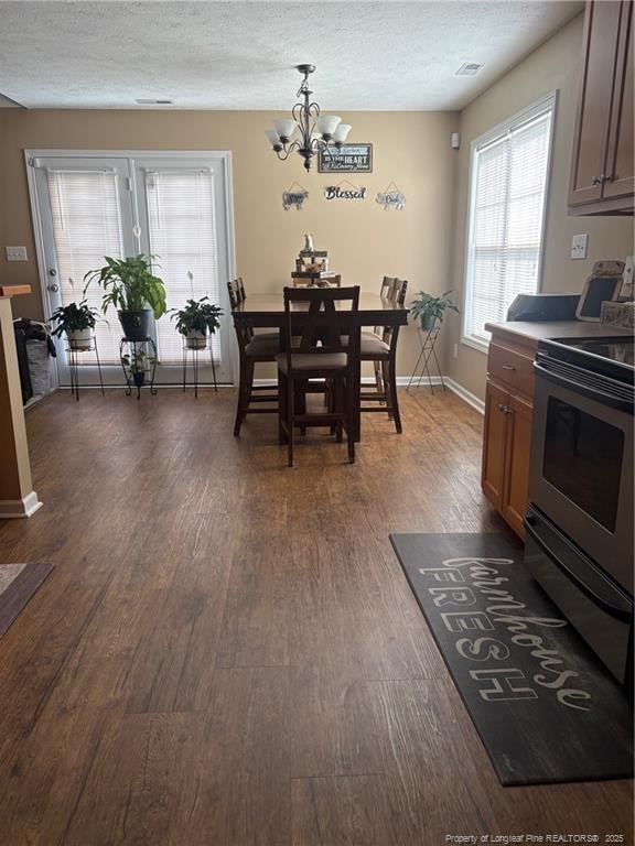 135 Paulownia Dr, Saint Pauls, NC 28384 - dining space with a chandelier, dark wood-type flooring, a textured ceiling, and baseboards