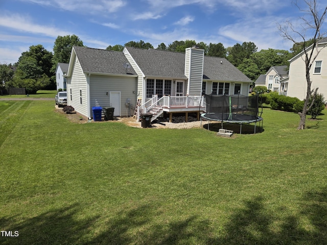 5810 Stardust Ct, Durham, NC 27712 - back of house featuring a chimney, a wooden deck, a trampoline, a shingled roof, and a yard