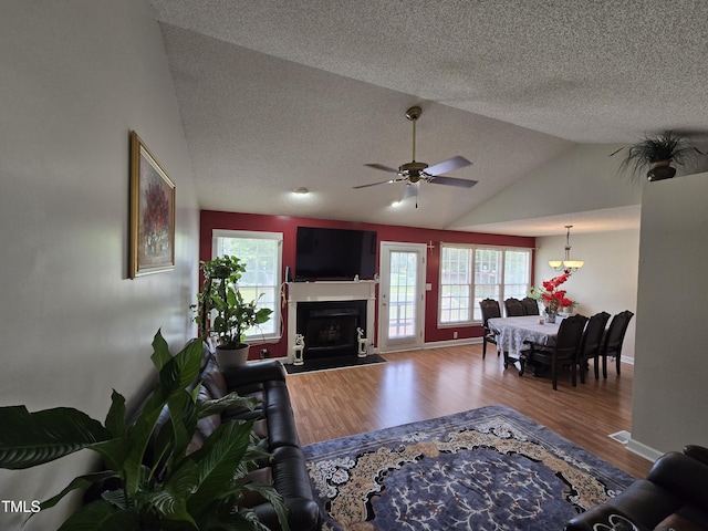 5810 Stardust Ct, Durham, NC 27712 - living area featuring a textured ceiling, lofted ceiling, a ceiling fan, wood finished floors, and a fireplace