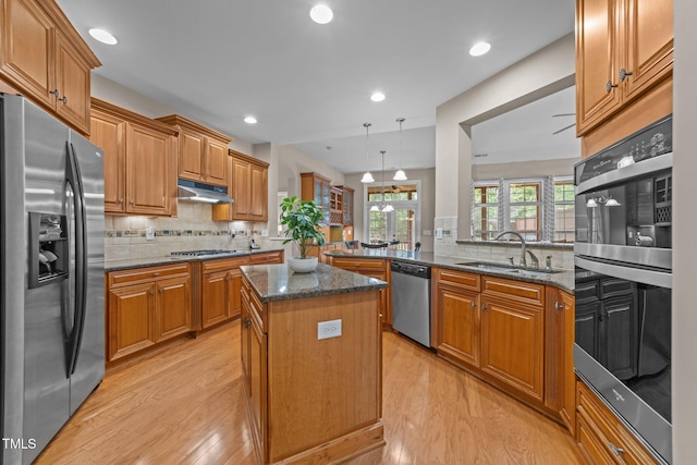 7768 Berry Crest Ave, Raleigh, NC 27617 - kitchen featuring appliances with stainless steel finishes, a sink, under cabinet range hood, light wood-type flooring, and a kitchen island